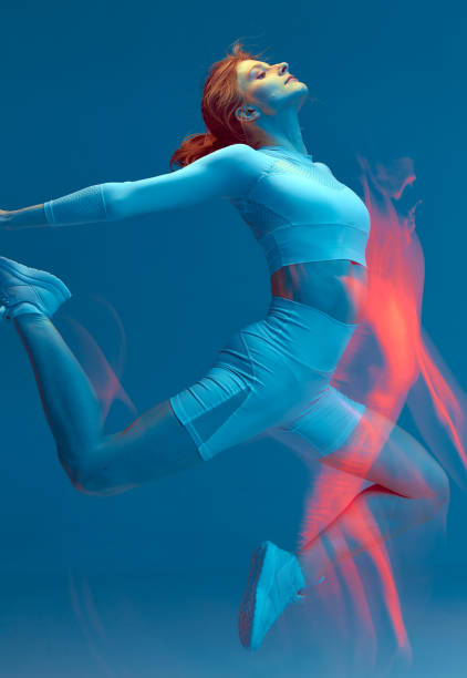 istock Girl jumps with her hands back. Long exposure effect. White sport suit on blue background. 1432407112