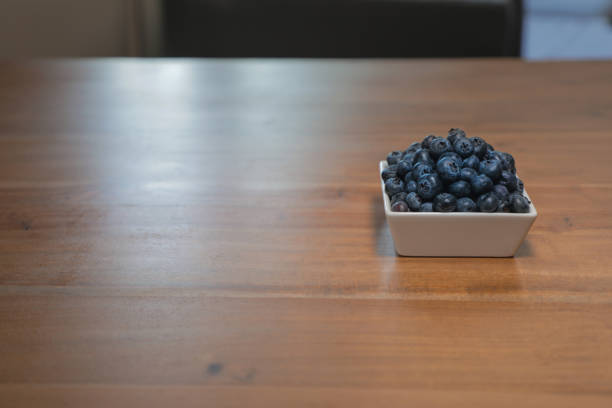 Ripe blueberries in square white dish in isolation offset with room for text