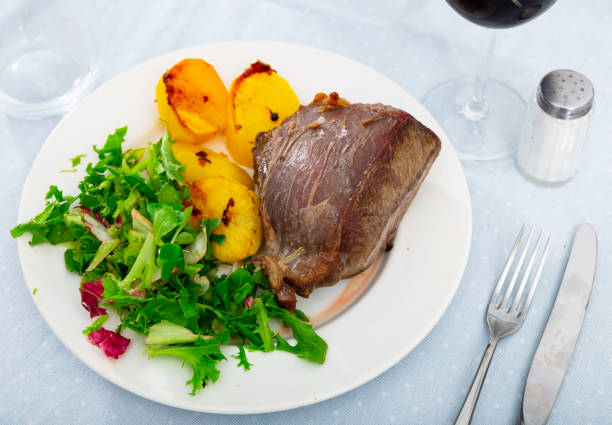 Appetizing roasted boneless beef served with baked potatoes and mixed greens salad