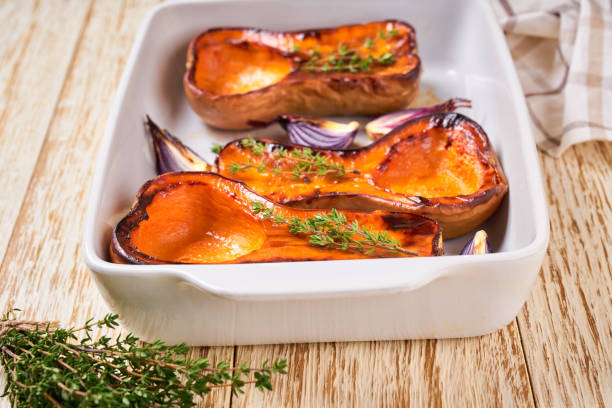 istock Baked pumpkin slices and thyme on a white baking sheet, close up. 1432411357