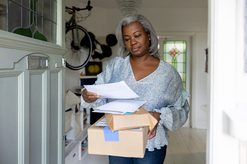 Mature woman at home getting packages and letters in the mail - domestic life concepts