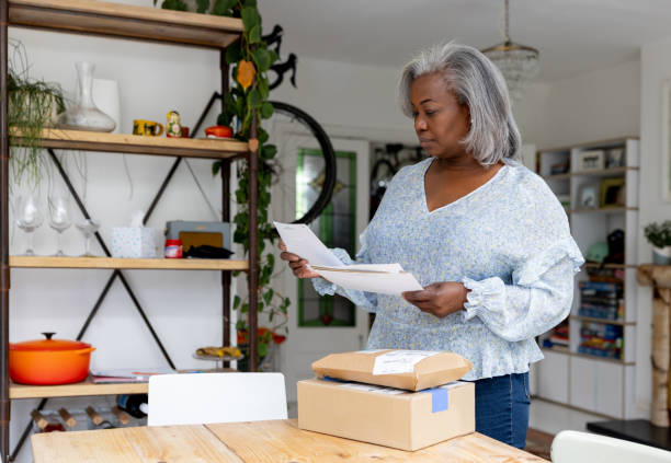 mulher em casa checando suas cartas e lendo uma carta - women mature adult black american culture - fotografias e filmes do acervo