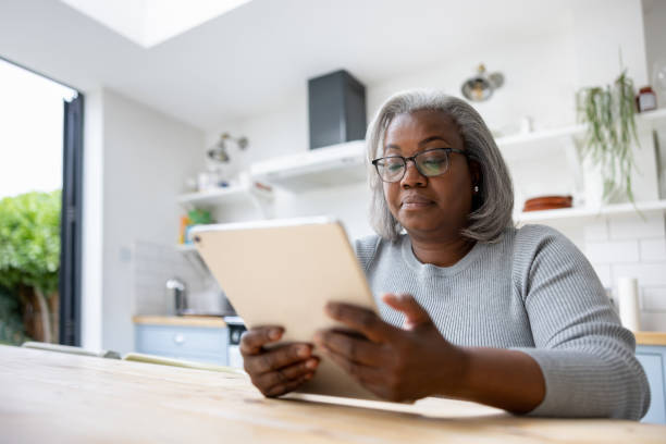 istock Mature woman at home reading on her tablet 1432413469