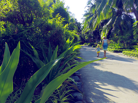 Mother and daughter walking in a tropical garden, retro toned