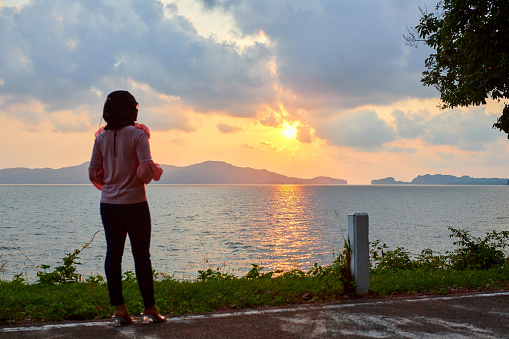 Rear view of muslim woman standing in peaceful moment of sunset at Mu Ko Phetra in Thailand