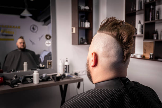 trendy man portrait. Punk styled man with Mohawk hairstyle against the background of a barbershop Young trendy man portrait. Punk styled man with Mohawk hairstyle against the background of a barbershop mohawk stock pictures, royalty-free photos & images