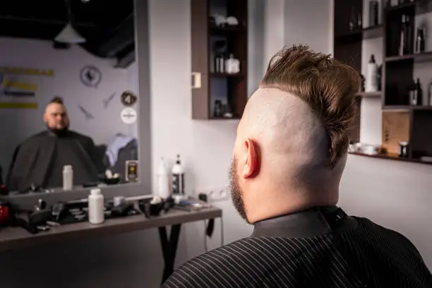 Photo of trendy man portrait. Punk styled man with Mohawk hairstyle against the background of a barbershop