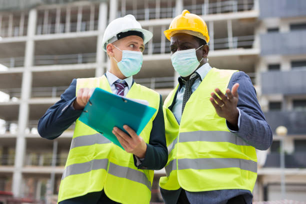 istock Portrait of an engineer and architect in protective mask with folder of documents at construction site 1432416996