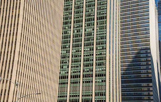 Close-up on a tall city office building with cloudy sky beyond.