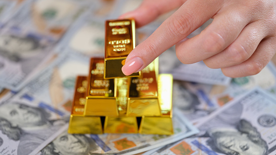 Woman hand puts golden ingot of dollar banknote. Favorable investment interest and deposit and financial income