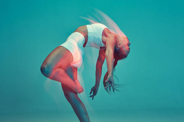 istock Expressive young woman enjoying dance in studio on blue background. 1432421878