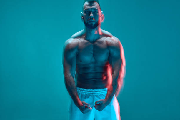 istock Muscular athletic man with naked torso showing his trained muscles in neon studio light. Long exposure. Copy space 1432421957