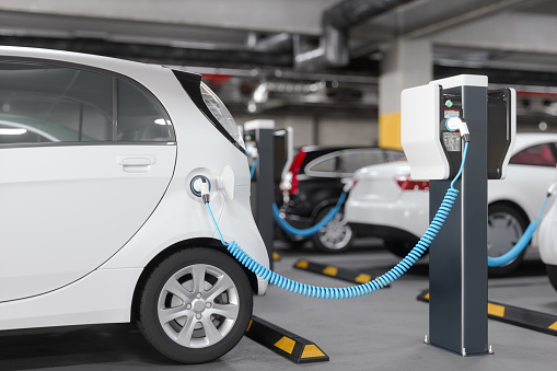 Close-up View Of Charging Electric Car In Parking Garage. Clean Energy Concept