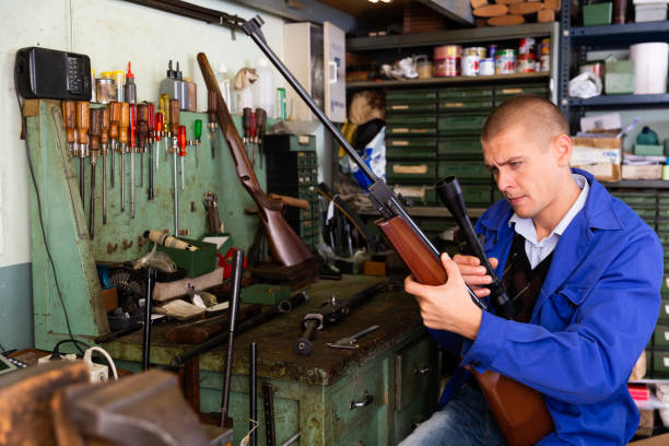 istock Gunsmith attaches a telescopic sight to rifle in weapons workshop 1432424744