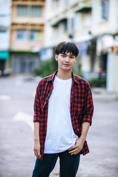 istock A young man in a striped shirt is standing on the street. 1432425265