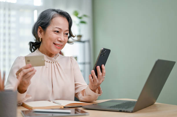 istock Attractive 60s aged-asian woman using her smartphone to pay her bills on payment application 1432426542