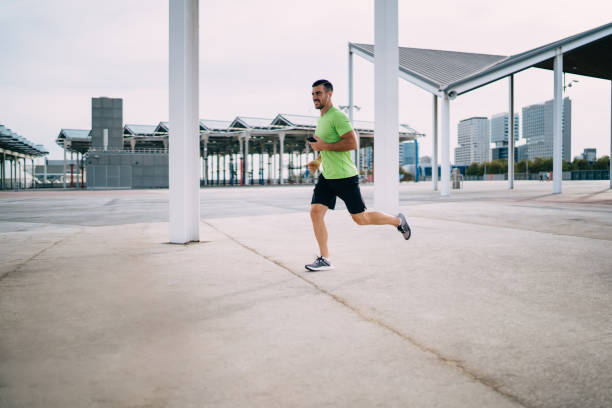 istock Determined man with smartphone and earphones jogging 1432426597
