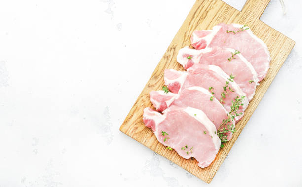 rohe schweinekoteletts, fleisch auf schneidebrett zum kochen vorbereitet. weißer küchentisch, draufsicht - veal raw meat pink stock-fotos und bilder