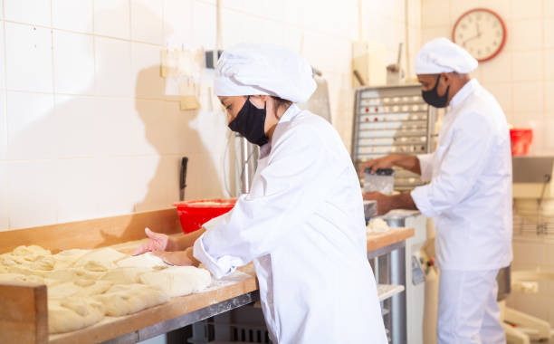 istock Female baker forming bread loaves from raw dough 1432426679