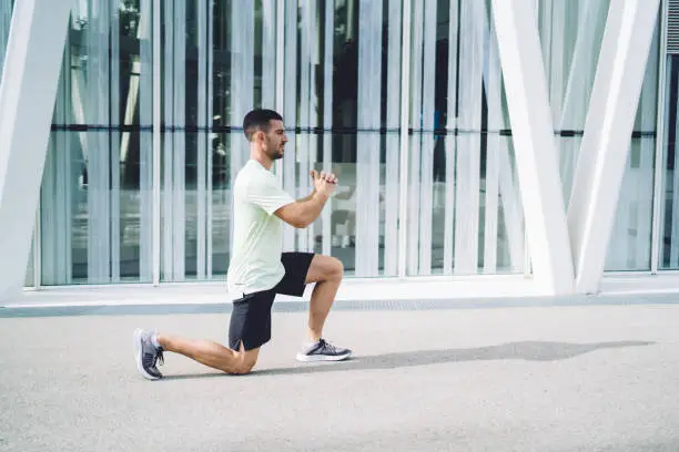 Photo of Confident  male athlete stretching legs before workout