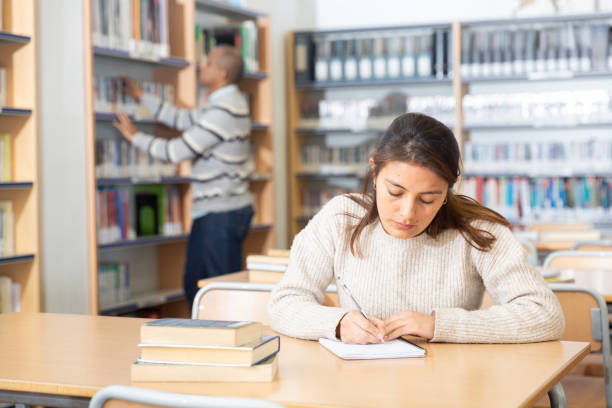 istock Young latin american woman studying in university library 1432428094