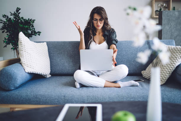 istock Surprised woman browsing laptop on sofa 1432428336