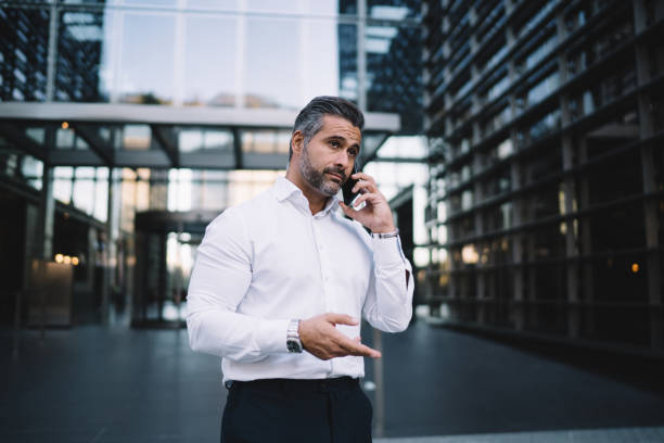 istock Serious male employee communicating with operator service for discussing corporate details using cellphone application outdoors, mature businessman calling to partner using roaming internet connection 1432429266