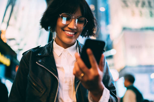 istock Millennial party blogger sharing publication with content information about nightlife in illuminated New York, prosperous influencer in electronic headphones watching streams video on mobile gadget 1432429391