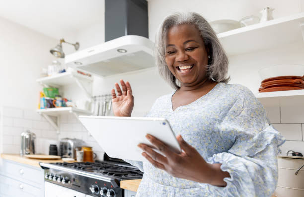istock Mature woman at home waving hello while talking on a video call 1432430424