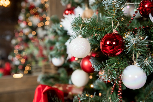 Árbol mágico y brillante. Interior de la casa de Navidad con árbol de Navidad. Bolas rojas y blancas colgando de ramas de pino. Luces festivas en el fondo de la pared de ladrillo. Concepto de Año Nuevo. photo