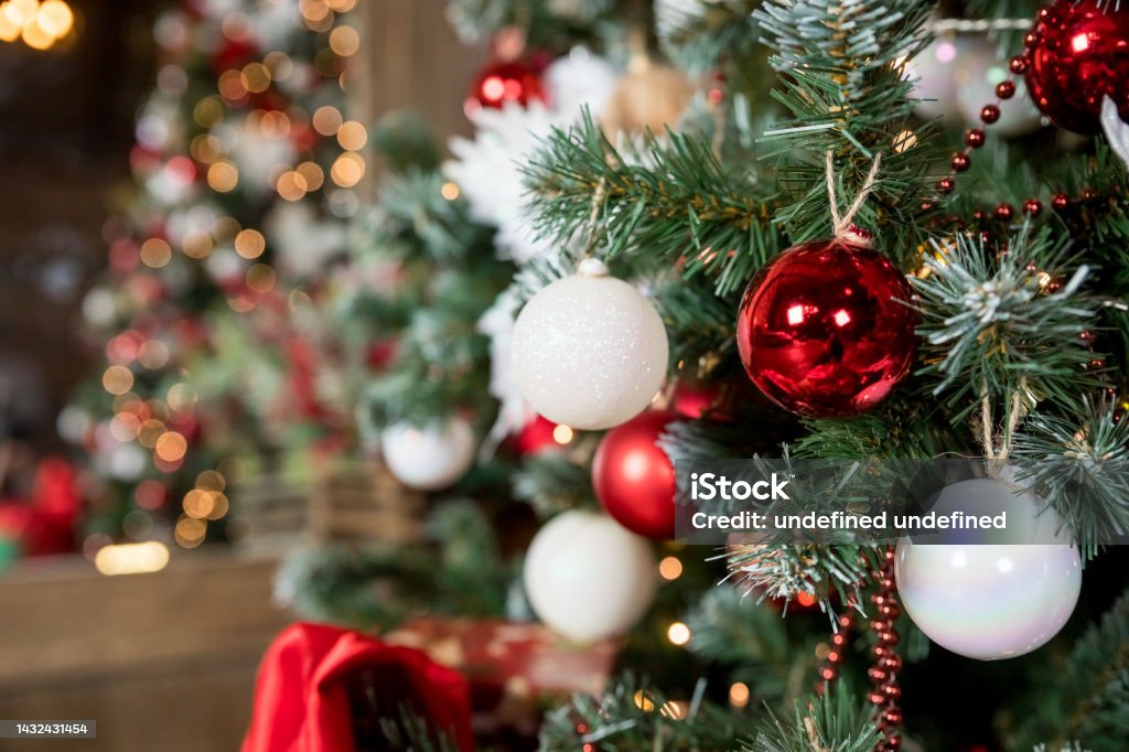 Magic glowing tree. Christmas home interior with Christmas tree. Red and white balls hanging on pine branches. Festive lights in the brick wall background. New Year concept. Magic glowing tree. Christmas home interior with Christmas tree. Red and white balls hanging on pine branches. Festive lights in the brick wall background. Christmas Tree Stock Photo
