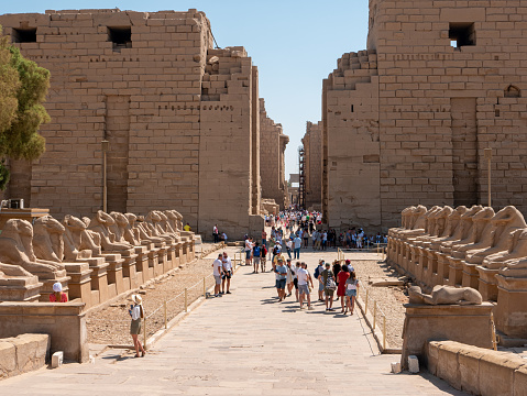 Luxor, Egypt - October 3, 2021: View of the Karnak Temple - a temple complex of ancient Egypt. Group of people walk and inspect the ancient ruins near the alley of the sphinxes.