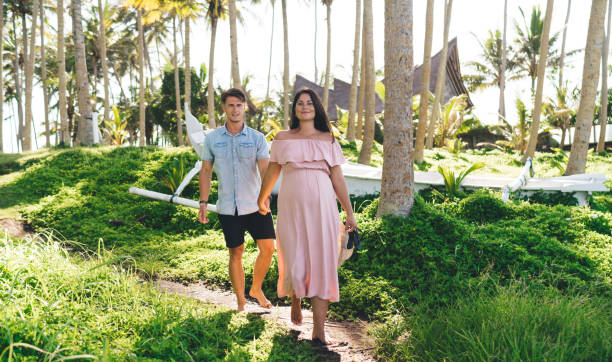 istock Positive expecting couple strolling along rural footpath in tropical park 1432433839