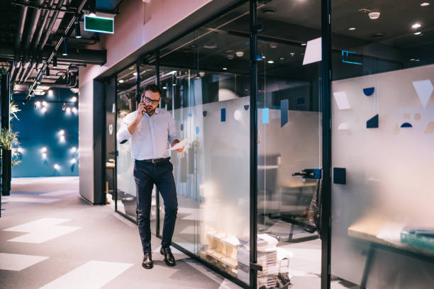 istock Dissatisfied businessman talking on smartphone in office corridor 1432433922