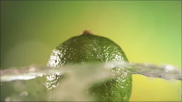Half Lime falling and splashing on white background. Food levitation concept. Slow Motion