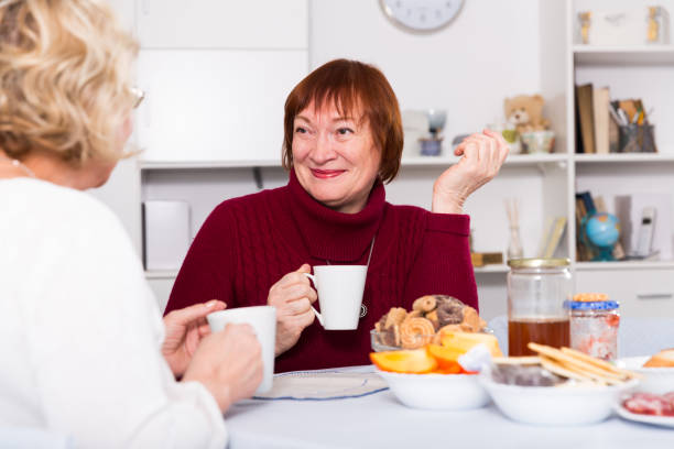 istock Smiling elderly woman drinking tea with female friend 1432437743