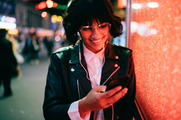 istock Happy hipster girl in optical spectacles checking shared video web content listening sounds in electronic headphones, trendy dressed blogger communicating with followers from website using smartphone 1432437745