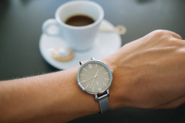 istock Selective focus of modern elegant designed silver wrist watch with minimalistic clock face and fashionable bracelet, cropped image of classical wristlet with accurate mechanism on table in coffee shop 1432438014