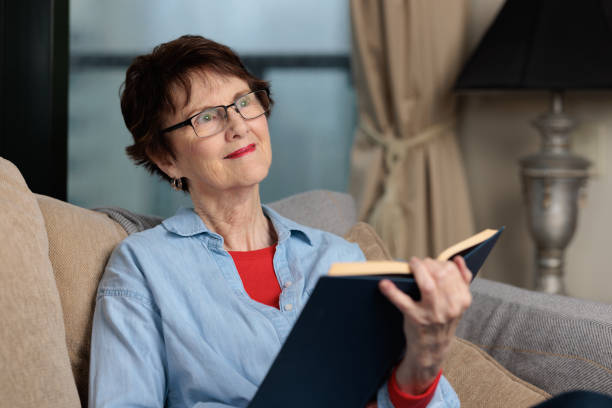 istock Smiling woman at home holding a book 1432438957