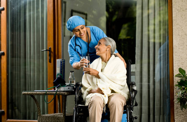 caregiver giving glass of water to old woman - wheelchair disabled senior adult female nurse imagens e fotografias de stock