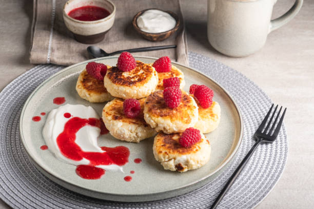istock Cheesecakes or syrniki on a round plate with raspberry, sour cream and raspberry syrup. 1432439096