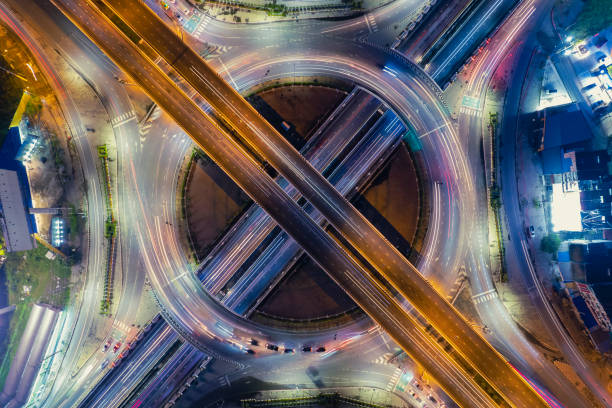 Aerial view of road interchange or highway intersection of Expressway top view, Road traffic an important infrastructure, car traffic transportation above intersection road in city night. stock photo
