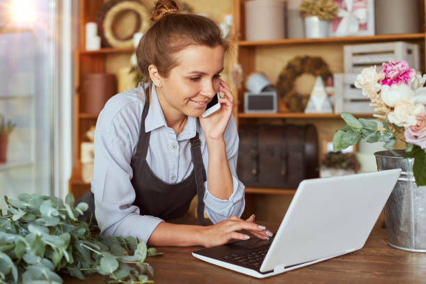 istock Pretty woman working at flower shop, using technology 1432439598