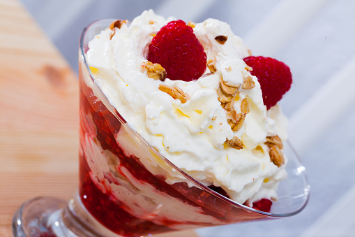 Traditional scottish cranachan with raspberry, whipped cream and cereal in glass