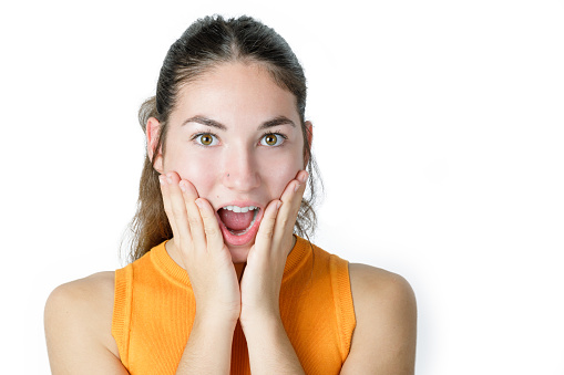 Portrait of surprised young woman with hands on face. Amazed young woman with opened mouth. Happiness and excitement concept