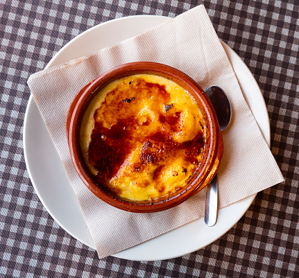 Portion of creme brulee or burnt cream served in bowl on table. Traditional French dessert.