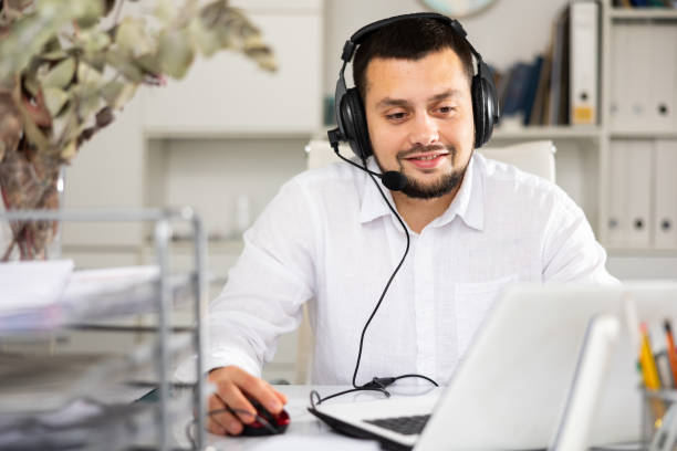 istock Smiling man with headset in his workplace in office 1432443377
