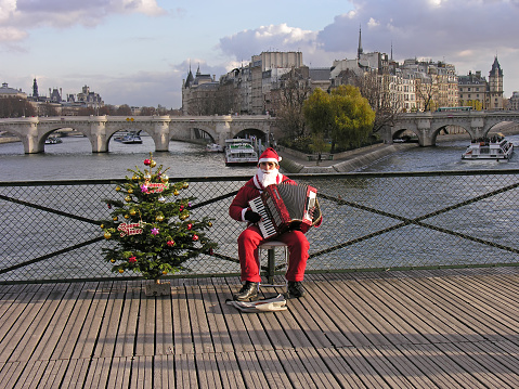 Paris, France - Decrmber 18, 2005: A young man dressed as Pere Noel plays the accordion on the Pont des Arts in Paris.
