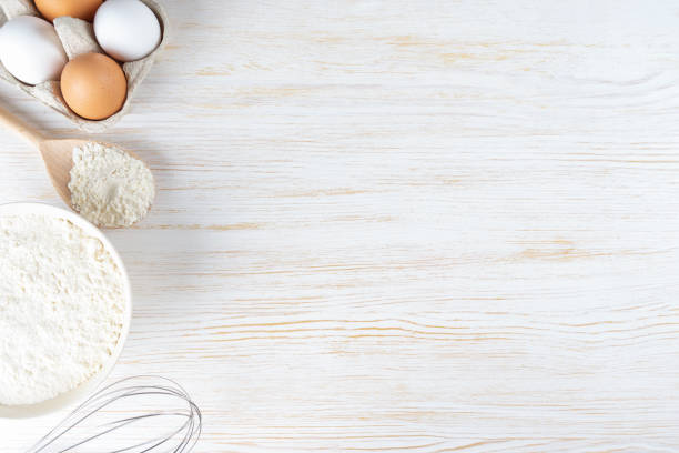istock Baking ingredients flour, eggs, milk, bakeware on white wooden background with copy space 1432452669
