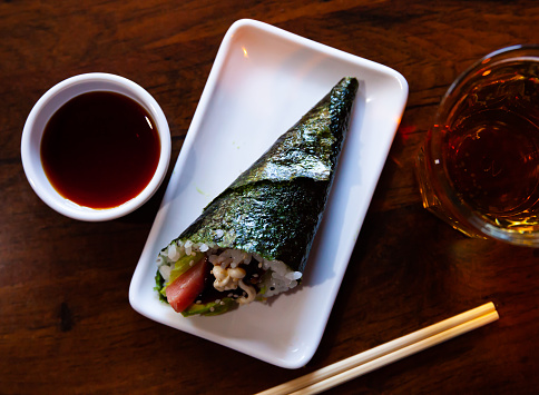 Traditional Japanese temaki - large cone-shaped piece of nori filled with rice, tuna and avocado